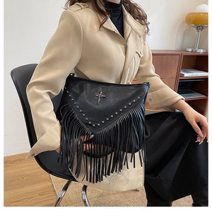 Détail du sac en similicuir noir avec pompon et badge croix en métal en décor de style