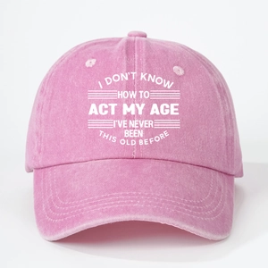 Detail of a pink washed cotton baseball cap with white humorous slogan text and stitching
