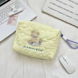 Close-up of quilted cosmetic bag with cute bear embroidery and purple zipper pull