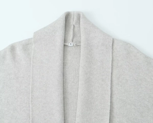 Detailed close-up of light grey knit cardigan shawl collar with size S woven label