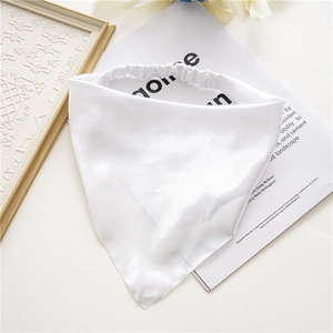 Detail shot of white satin triangular headscarf with elastic band on styled background