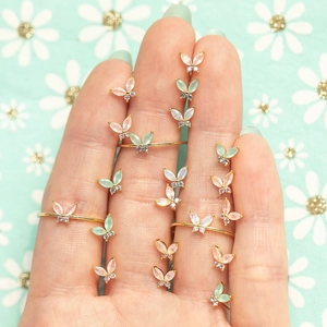 Golden butterfly earrings and rings set in colorful macaron shades on mint background