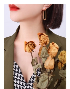 Detail view of a model wearing a minimalist 18k gold-plated rectangular earring in a retro style