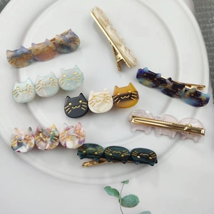 Close-up of cat-shaped acetate hair clips with marble patterns in a white dish