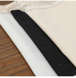 Close-up of cotton linen placemats with fringe edge in white, black and beige colors