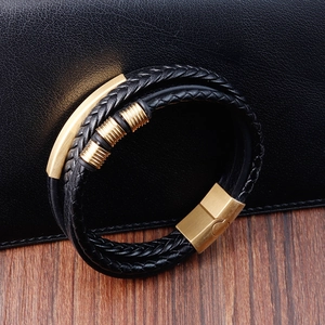 Close-up of black braided leather multi-layer bracelet with gold metal clasp on dark wood