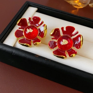 Detail of vintage red enamel flower earrings with gold edges in a jewelry box