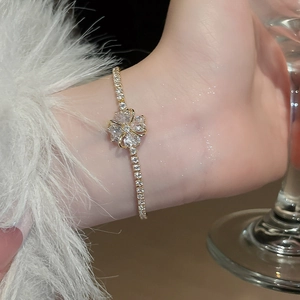Close-up of gold clover bracelet with zircon crystals on a tennis chain worn on wrist