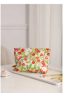 Neceser elegante con estampado floral de bayas y pinceles dorados en una bandeja chic.
