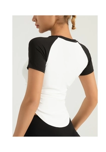 Back view of slim fit black and white raglan sleeve yoga top with curved hemline