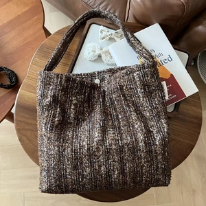 Macro shot of brown tweed texture and silver snap fastener on a retro shoulder bag