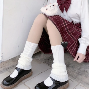 Close-up of white knitted Lolita leg warmers styled with black Mary Jane shoes