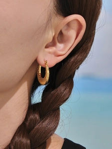 Macro view of 18K gold plated hoop earrings with fish scale texture on a model