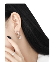 Close-up of elegant double hoop silver earrings and rectangle zircon ring on a model