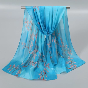 Détail d'une écharpe en mousseline bleue semi-transparente avec motifs floraux roses