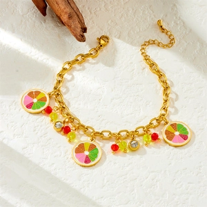 Gold chain bracelet with fruit enamel charms and rhinestone beads on white stone