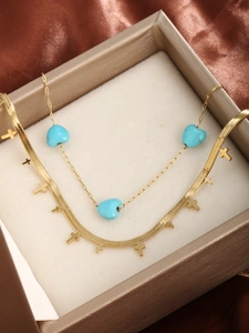 Close-up of gold double-layer necklace with turquoise heart charms and cross pendants