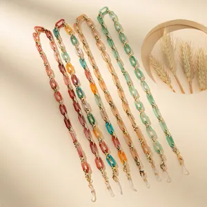 Set di catenelle per occhiali in acrilico con maglie in resina e clip dorate su sfondo beige
