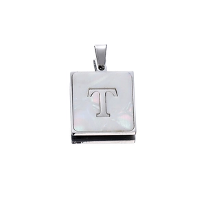 Macro detail of a square stainless steel letter T pendant with white mother of pearl inlay