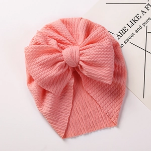 Detail of baby turban hat featuring pink ribbed knit texture and large bow decoration