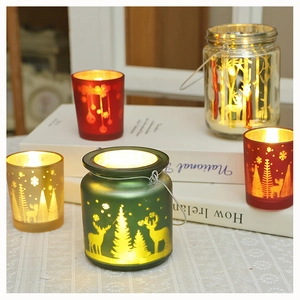 Close-up of frosted glass Christmas candle holders with deer and tree laser engravings