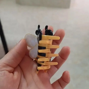 Detailed view of bee-shaped hair claw clip with yellow and black striped patterns
