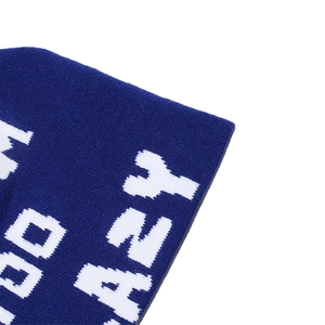 Close-up of navy blue knit beanie showing white jacquard letter texture and fabric detail