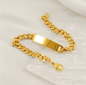 Dettaglio di un bracciale a catena cubana in acciaio dorato con una piastra lucida incidibile