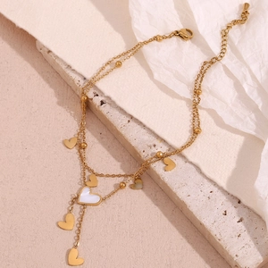 Detail of 18K gold-plated double-layer anklet with heart charm and white shell tassel