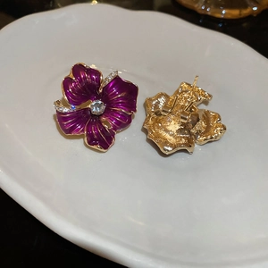Détails macro de boucles d'oreilles fleurs mauves, plaqué or et zircons brillants