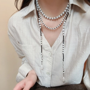 Close-up of layered necklace with white pearls, black beads, and water drop pearl pendant