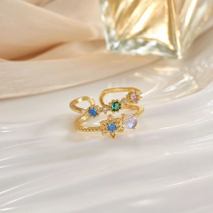 Detail of gold open rings featuring colorful crystals and opal on luxury silk background