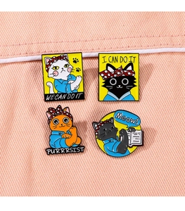 Detailed close-up of four cat enamel pins with motivational quotes on pink denim fabric