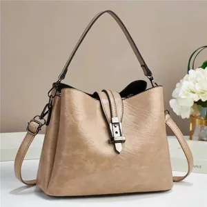Detail of apricot bucket bag with silver metal buckle and glossy faux leather texture