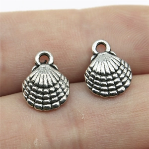 Silver shell-shaped alloy pendants for DIY jewelry making shown on a fingertip