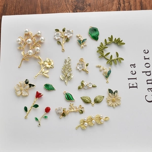Detail of rose and leaf enamel charms for DIY jewelry making on white background