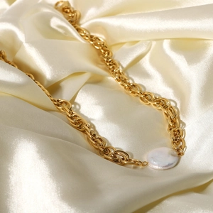 Detail of 18K gold-plated stainless steel chain with round pearl on silk background