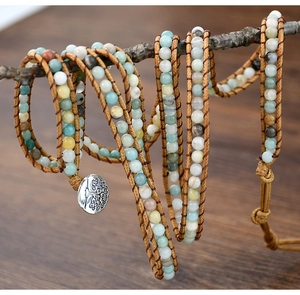 Detail of multi-layer stone wrap bracelet with tree of life charm on wooden branch