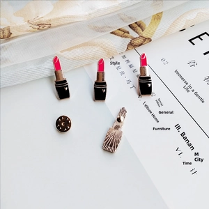Detail of three lipstick enamel pins with heart accents and butterfly clutch back