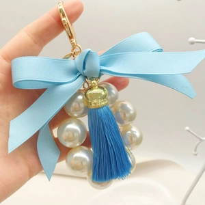 Fashionable keychain with light blue ribbon bow, white pearls, and dark blue fringe tassel