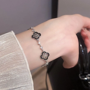 Détail du bracelet trèfle vintage avec breloques noires et diamants au poignet