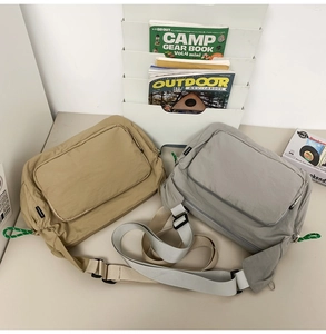 Detail of khaki and grey waterproof nylon messenger bags with adjustable straps on a desk