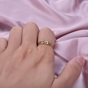 Polished gold LOVE letter ring in 304 stainless steel on a soft pink silk background