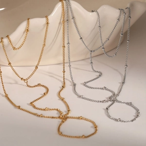 Elegant gold and silver stainless steel beaded hand chains draped on white ceramic props