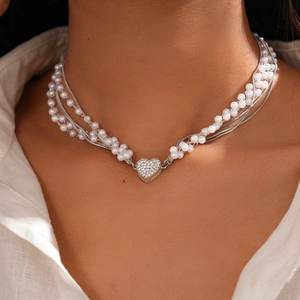 Détail d'un collier multicouche avec pendentif cœur en strass brillant et perles