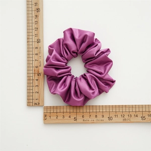 Detailed top view of a purple satin hair scrunchie with a ruler showing 10cm diameter