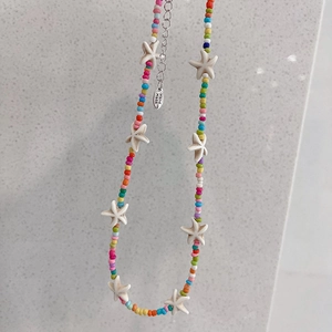 Detailed view of handmade bohemian beaded necklace with white starfish pendants and lobster clasp
