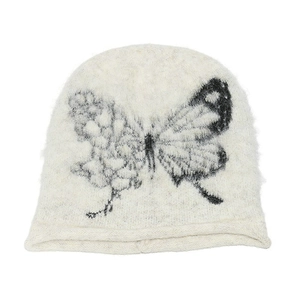 Detail of cream knitted beanie featuring black butterfly pattern and fuzzy mohair texture