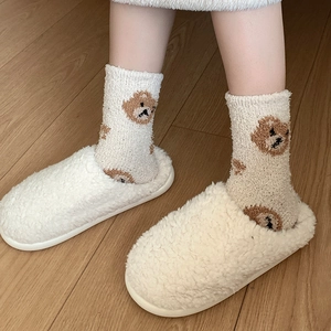 Detail of coral fleece winter socks with cute bear pattern on wooden floor