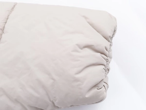Close-up of light beige quilted fabric and elastic cuffs on a hooded winter jacket